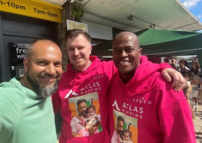 shaz the owner of seven hair and body smiling at the camera with two men wearing pink fundraising jumpers