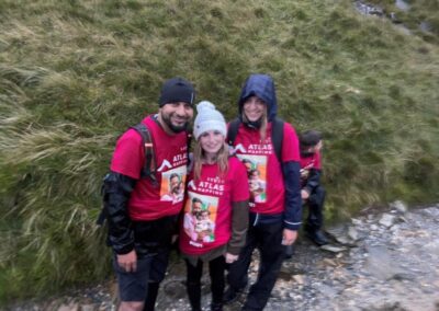 a man and two women smiling at the camera standing on mount snowden wearing pink fundraising shirts for the seven hair and body mount snowden challenge