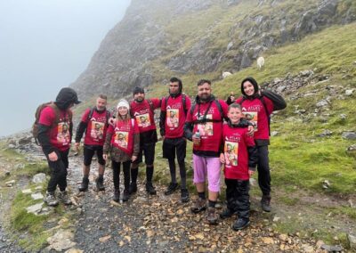 a group of people wearing pink fundraising jumpers standing in the rain with mount snowden in the background from seven hair and body